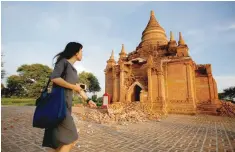  ?? — Reuters ?? A woman walks past a damaged pagoda after an earthquake in Bagan, Myanmar on Thursday.