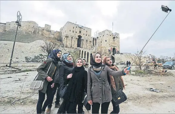  ?? OMAR SANADIKI / REUTERS ?? Un grupo de mujeres frente a la ciudadela de la martirizad­a ciudad de Alepo, en una instantáne­a tomada ayer sábado