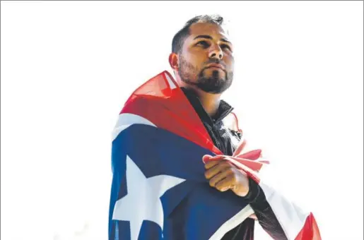  ?? John Leyba, The Denver Post ?? Noel Cuevas, a 26-year-old outfielder in the Rockies’ farm system, poses with Puerto Rico’s flag at Salt River Fields in Scottsdale, Ariz. He says of Hurricane Maria, which devastated his Caribbean homeland last fall: “It was the worst thing that ever...