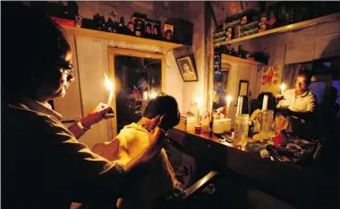  ?? Associated Press photos ?? An Indian barber holding a candle gives a haircut to a customer at his shop in Kolkata on Tuesday. India’s energy crisis
cascaded over half the country when three of its regional grids collapsed, leaving 620 million people without power.