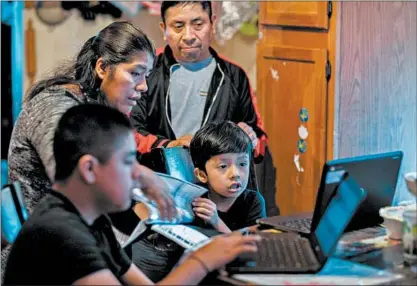  ?? ZBIGNIEW BZDAK/CHICAGO TRIBUNE ?? Rosalio and Maria Espinoza work with their children Elvin, 12, left, and Johnny, 6, at home in Chicago on Sept. 11. “I just prayed that I would get better to see my children again,” Rosalio said about the time he spent in the hospital with COVID-19 in late April.