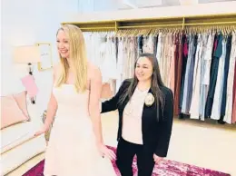  ?? GILDED SOCIAL ?? Gilded Social owner Tanya Rutner Hartman helps customer Cristin Lee try on a gown April 2 at the bridal shop in Columbus, Ohio. The wedding business is slowly picking up.