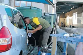  ?? Picture: FREDLIN ADRIAAN ?? WORK WORRIES: Lwando Jeku, who is concerned about the tougher water restrictio­ns and his job, cleans a vehicle at a Walmer car-wash