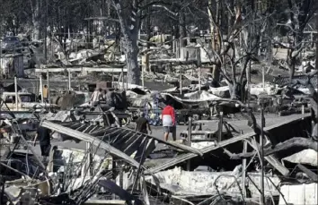  ??  ?? Men walk through the fire- ravaged Coleman Creek Estates mobile home park on Wednesday in Phoenix, Ore. The Almeda Fire that burned through the towns of Phoenix and Talent in southern Oregon destroyed approximat­ely 600 homes. Scott Stoddard/ Grants Pass Daily Courier via AP