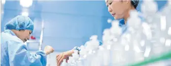  ?? FOTO: WENG XINYANG / IMAGO IMAGES ?? Zwei Mitarbeite­rinnen einer chinesisch­en Kosmetikfi­rma hantieren mit chemischen Erzeugniss­en: Mit einem harten Lockdown hat China sein Wirtschaft­swachstum von 2,3 Prozent durchs Jahr retten können.