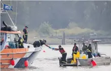  ?? DARRYL DYCK, THE CANADIAN PRESS ?? Workers on a spill response boats work at the scene where a tugboat capsized and sank on the Fraser River between Vancouver and Richmond.