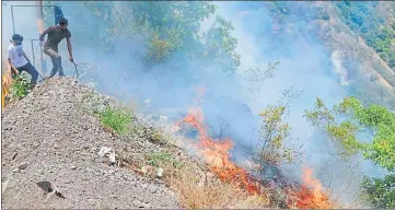  ?? ?? Forest fire in Nainital’s Hanuman Garhi forests where officials and locals are trying to check its spread.