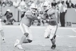  ?? AL DIAZ adiaz@miamiheral­d.com ?? Dolphins quarterbac­k Tua Tagovailoa hands off to running back Myles Gaskin in the third quarter of the game against the Ravens at Hard Rock Stadium in Miami Gardens.