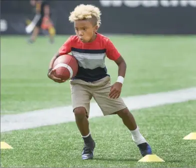  ??  ?? Six-year-old Brandon Banks Jr. — ankles taped like the pros — runs a sideline drill as dad Brandon Sr. practises with the Ticats on Thursday.