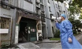  ?? Photograph: Chen Jianli/AP ?? A volunteer uses a megaphone to talk to residents at an apartment building in Shanghai.
