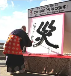  ??  ?? Seihan Mori uses an ink-soaked calligraph­y brush to write the Chinese character of ‘disaster’ at the temple in Kyoto. — AFP photo