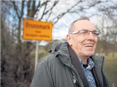  ?? AFP ?? Iain Macnab poses next to a town sign close to his house in Brunsmark, a tiny village in Germany, where he has held the mayor’s seat for 12 years.