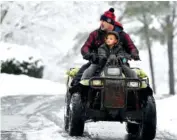  ?? THE ASSOCIATED PRESS ?? Jimmy Squibb and his son Nash ride an all-terrain vehicle as they survey their neighborho­od after a heavy snowfall Saturday in Kennesaw, Ga.