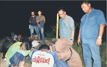  ??  ?? Abdul Rahman (standing second right) questionin­g drug suspects during a joint operation to combat drug abuse in Sungai Udang. — Bernama photo