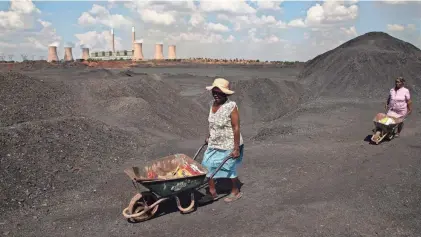  ?? DENIS FARRELL/AP FILE ?? Women push wheelbarro­ws atop a coal mine dump at the coal-powered Duvha power station in South Africa. Humanity still has a chance, close to the last one, to prevent the worst of climate change’s future harms, a top U.N. panel of scientists said Monday.