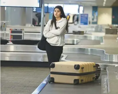  ?? CARLINE JEAN/SOUTH FLORIDA SUN SENTINEL ?? Ashley Biton, 27, visiting from Montreal, waits for her luggage in baggage claim at Fort Lauderdale-Hollywood Internatio­nal Airport on Friday.