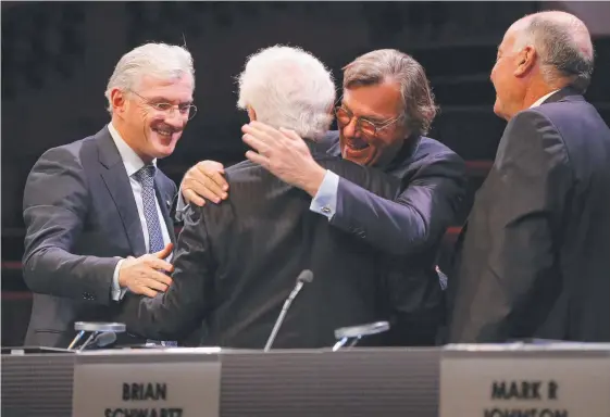  ??  ?? Sir Frank Lowy and Peter Lowy embrace while flanked by Steven Lowy and and Mark R Johnson. Picture: Hollie Adams/The Australian