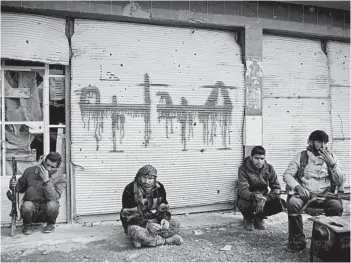  ?? FELIPE DANA/AP ?? U.S.-backed fighters of the Syrian Democratic Forces sit outside a building Saturday in Baghouz, Syria. The SDF says the end to the extremist group ISIS will happen soon.