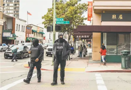  ?? Photos by Stephen Lam / The Chronicle ?? Top: Armed security members from Goliath Protection Group, contracted and funded by a GoFundMe campaign, patrol Webster Street in Oakland’s Chinatown district.