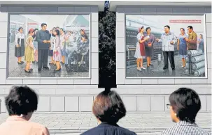  ??  ?? BELOW Overseas North Korean citizens pay their respects in front of Kimthemed illustrati­ons at a silk factory in Pyongyang.