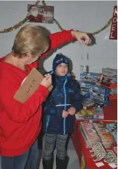  ??  ?? Western Developmen­t Museum volunteer Sheryl shows off a Christmas tree ornament to Kids Secret Shopping patron Georgia.