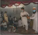  ??  ?? Kashmiri men carry rice plates before serving them to guests.