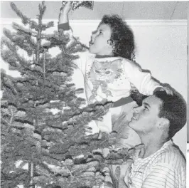  ??  ?? Ruby Patey’s daughter, Rana, pins the star atop their tree. Patey now lives in Grand Falls-windsor, N.L., but grew up in St. Jacques, where her Christmas tree would magically appear on Christmas morning.