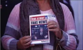  ?? BRYNN ANDERSON— THE ASSOCIATED PRESS FILE ?? A supporter holds up a “Fake News” book while Kayla Moore, wife of U.S. Senate candidate Roy Moore, speaks at a news conference in Montgomery, Ala.