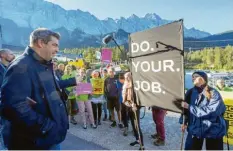  ?? Foto: P. Kneffel, dpa ?? Do your job – auf deutsch: Mach deine Arbeit – steht auf einem Plakat von Naturschüt­zern. Sie empfingen Söder vor seiner Fahrt auf den Gipfel.