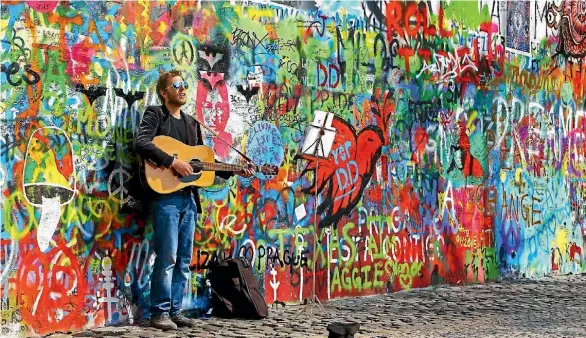  ?? ISTOCK ?? A young musician plays at the John Lennon wall in Prague.