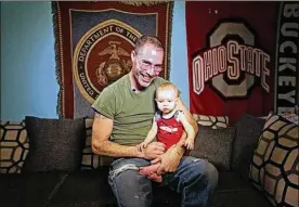  ?? DORAL CHENOWETH III / ?? Rick Cain, a Marine who had two confirmed kills while clearing an Iraqi city of insurgents in 2005, holds his daughter Genevieve at their home in Delaware.