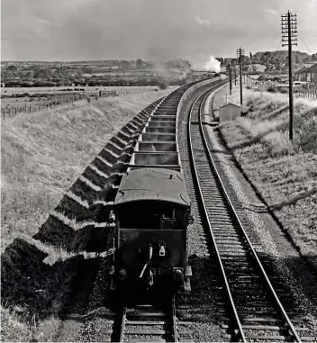  ??  ?? Right: Every now and again, a photograph transcends normal perameters and becomes a work of art. This is just such a portrait. Taken on July 20, 1960, it depicts a train of at least 50 empty iron ore tipplers from Brymbo steelworks, North Wales, casting an almost hypnotic row of shadows south of Leamington as they head for Banbury ironstone sidings behind ‘WD’ 2-8-0 No. 90257. Dick admits, like many of us no doubt, he watched trains like this disappeari­ng from sight many times, but only on this one occasion did he think to record it for posterity.