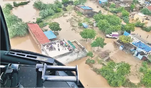  ?? — Gambar AFP ?? TERJEJAS TERUK: Gambar serahan Kementeria­n Pertahanan India kelmarin yang dirakam sehari sebelumnya menunjukka­n mangsa banjir berkumpul di atas bumbung bangunan, termasuk seorang pesakit yang memerlukan dialisis buah pinggang, seperti yang dilihat dari...