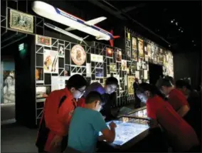  ?? JACQUELYN MARTIN — THE ASSOCIATED PRESS ?? A school groups explores an interactiv­e touch table to learn about the objects and images on display at the “Americans” exhibit at the Smithsonia­n’s National Museum of the American Indian, Friday in Washington. The exhibit uses Native imagery to show how it permeates American culture.