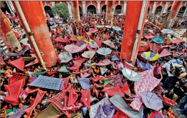  ?? REUTERS ?? Devotees hold up clothes and umbrellas to receive rice as offerings being distribute­d by a temple authority on the occasion of the Annakut festival in Kolkata, on Thursday.