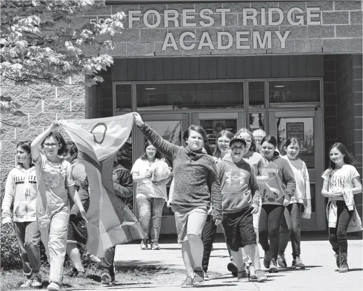  ?? KATHY JOHNSON ■ SALTWIRE ?? Members of the Gay Straight Alliance Club at Forest Ridge Academy in Barrington carry the Pride flag out to the school’s flag pole for a flag raising ceremony in June 2022.