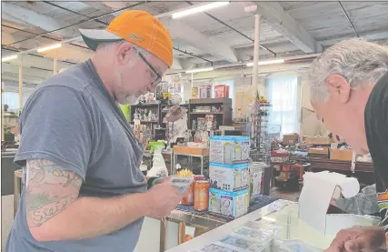  ?? DANIEL DRAINVILLE/THE DAY ?? Phil Taylor of Norwich, right, inspects baseball cards brought in by a customer Sunday at Dan Steighner’s shop at the College Mart Flea Market. Steighner and Taylor have both collected cards since they were kids.