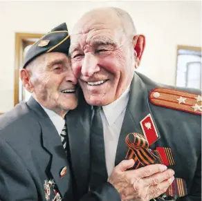  ?? JOHN MAHONEY ?? David Ficherman, left, hugs fellow veteran Alexander Morozov. The Immortal Regiment recalls a period of idealism and sacrifice.