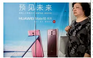  ?? — Reuters ?? Under fire: A woman walking past an advertisem­ent on an elevator showing Huawei Mate 10 series phones with a camera system co-developed with Leica in Shanghai.