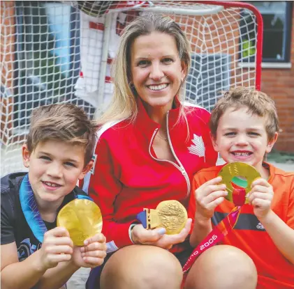  ?? JOHN MAHONEY ?? Kim St-pierre and her boys Liam, left, and Ayden hold her three Olympic gold medals at her home in the Saint-laurent borough of Montreal on Friday, a day after St-pierre learned she was being inducted to the Hockey Hall of Fame. She is the first female goaltender to receive the honour.