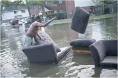  ?? — Reuters ?? Vince Ware moves his sofas onto the sidewalk from his house which was left flooded from Tropical Storm Harvey in Houston, Texas.