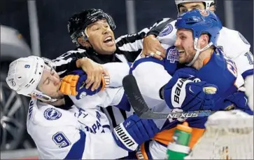  ?? Frank Franklin I I Associated Press ?? LINESMAN Jay Sharrers tries to separate the Lightning’s Tyler Johnson ( 9) and Islanders’ Casey Cizikas.