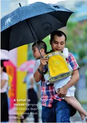  ??  ?? A father inHainan carrying his son on their way home from school