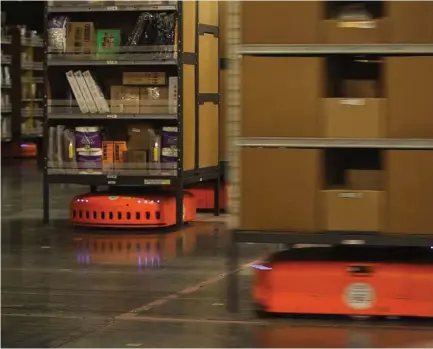  ??  ?? Amazon’s robots scurry by as they move merchandis­e at a fulfillmen­t center in DuPont, Wash. The KIVAs weigh 800 pounds each and can carry up to 3,000 pounds