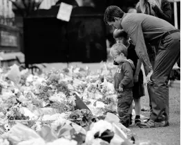  ?? AP ?? Mourners lay flowers on a wall at the Botanical Gardens in Christchur­ch, New Zealand. A steady stream of mourners paid tribute at a makeshift memorial to the 50 people slain by a gunman at two mosques in Christchur­ch.