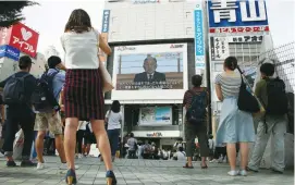  ?? (Kim Kyung-Hoo/Reuters) ?? PEOPLE ON THE streets of Tokyo watch a large screen showing Japanese Emperor Akihito’s video address yesterday.