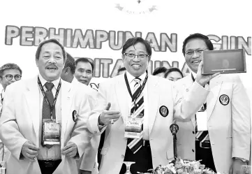  ?? - Photo by Tan Song Wei ?? Abang Johari (centre) showing the tablet that was used to officiate Saberkas tri-annual general assembly at Kuching Hilton yesterday. Also seen are Sagah (left) and Dr Abdul Rahman.