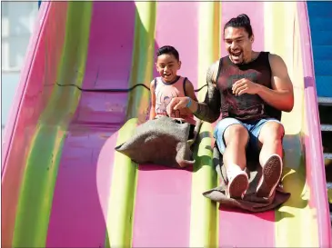  ?? FILE PHOTO BY JOEL ROSENBAUM — THE REPORTER ?? Uriah Maene, 4, and his uncle, Val Leelo, both of Dixon, fly down the giant slide ride along the midway at the 2019 Dixon May Fair. After being canceled for the last two years because of the COVID-19pandemic, the fair returns May 5to 8.