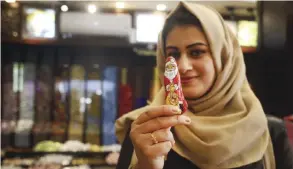  ??  ?? GAZA CITY: A Palestinia­n Muslim woman poses for a photo holding a chocolate bearing an image of Santa Claus at a shop. — AFP