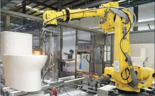  ?? SONG WEIWEI / XINHUA ?? An industrial robot, supported by artificial intelligen­ce and 5G technologi­es, puts finishing touches to a western commode at a production facility in Quanzhou, Fujian province, on Jan 13.